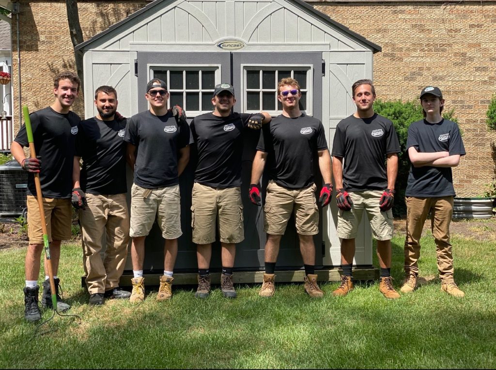 Junk Remedy Team Posing in Front of a Shed with Yard Waste Tools